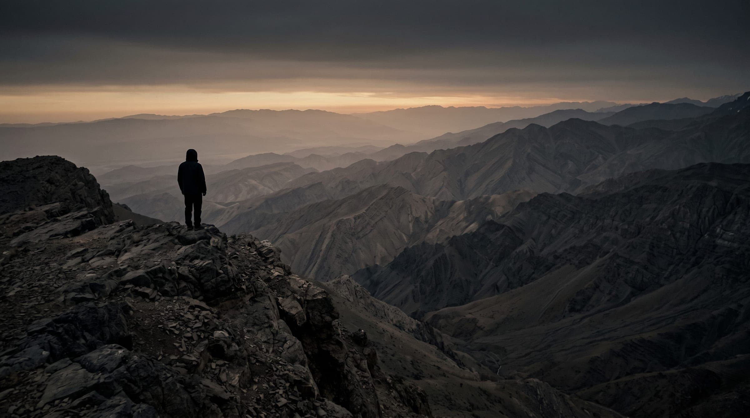 A lone figure on a rocky ridge above the Zagros mountains at first light